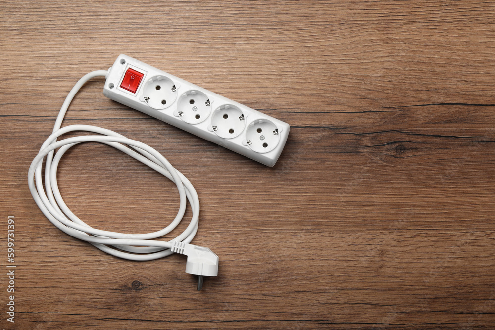 Power strip with extension cord on wooden floor, top view. Space for text Power strip with extension cord on wooden floor, top view. Space for text