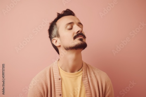 Portrait of a handsome young man with closed eyes on a pink background