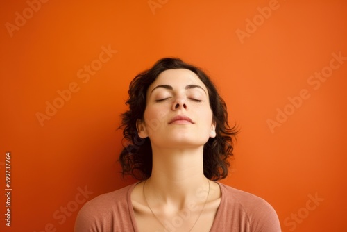 Portrait of a young woman with closed eyes on a orange background