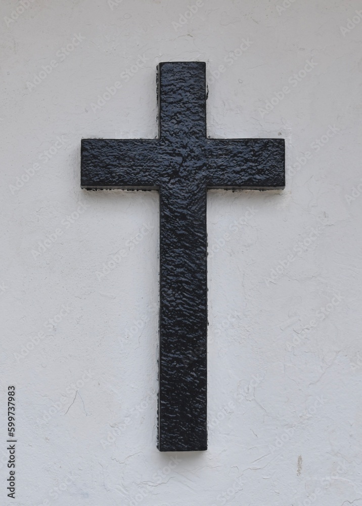 Stone carved black cross on a white wall