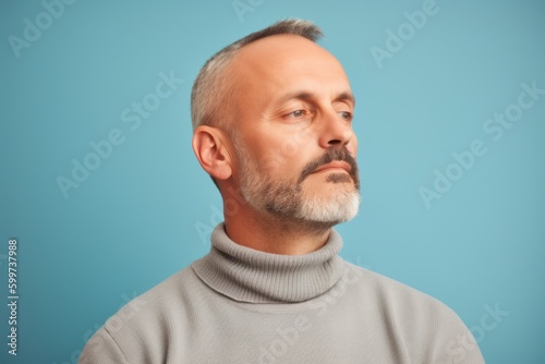 Portrait of a mature man in a gray sweater on a blue background