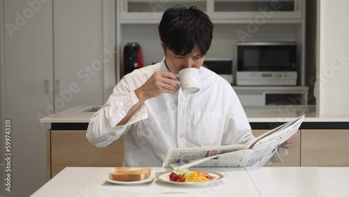 新聞と朝食を食べる男性