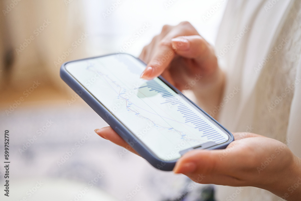 スマートフォンで為替チャートを確認する女性の手元 スマートフォンで為替チャートを確認する女性の手元