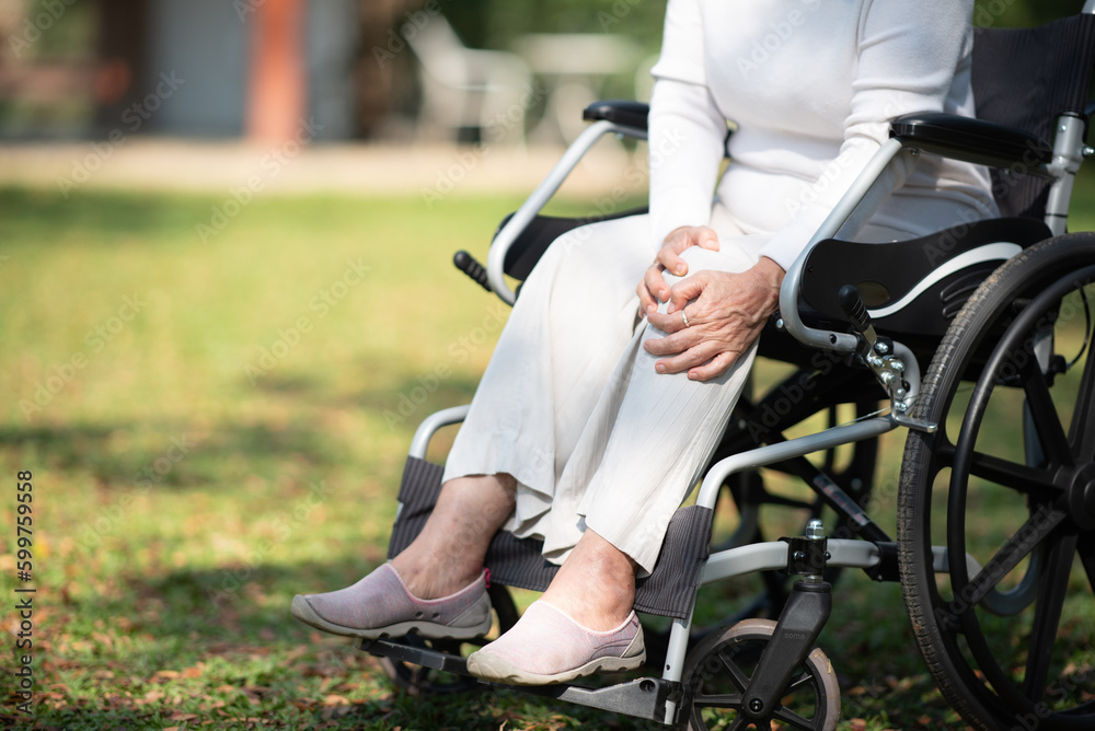 Asian old woman sitting on a wheelchair outdoors in the garden There is pain in the heart Asian old woman sitting on a wheelchair outdoors in the garden There is pain in the heart