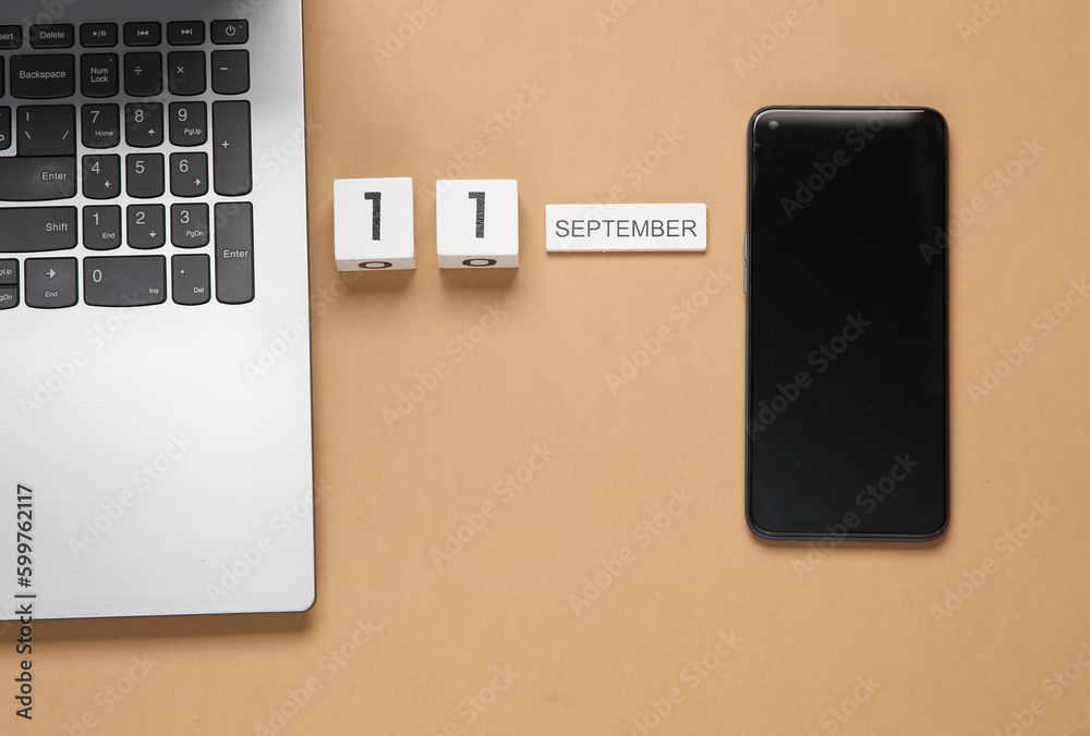 White wooden block calendar with date september 11 and laptop with smartphone on beige background. White wooden block calendar with date september 11 and laptop with smartphone on beige background.