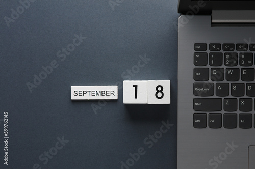 White wooden block calendar with date september 18 and laptop on gray background. Business, deadline, planning photo