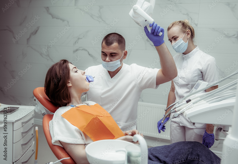 Professional doctor dentist with a woman assistant examines the teeth
