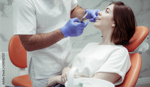 Professional dentist selects the color tone of the teeth for the female patient in the dental clinic