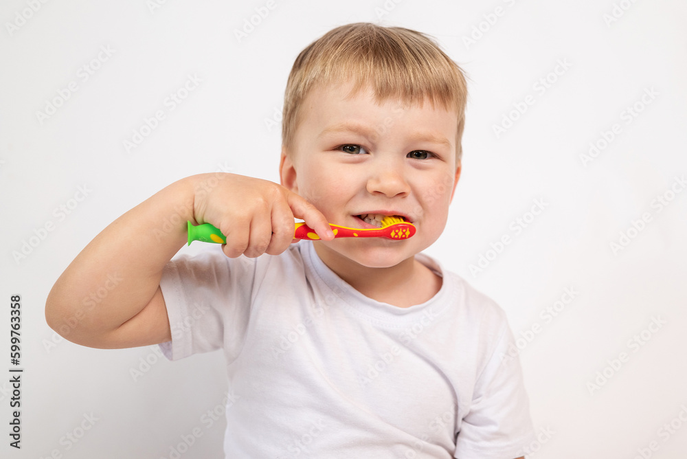 Child with a toothbrush on a white background brushes his teeth and smiles close-up, the concept of caring for children's milk teeth, personal hygiene procedure. Child with a toothbrush on a white background brushes his teeth and smiles close-up, the concept of caring for children's milk teeth, personal hygiene procedure.