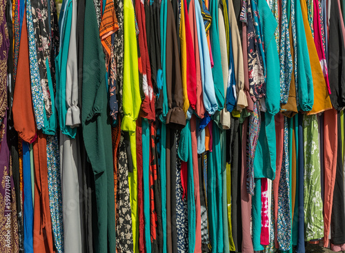 used colorful clothing hanging on a rack at a flea market