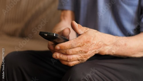 hands of a pensioner switching tv channels with a faulty tv remote control, an angry elderly man hits a faulty tv remote control. lifestyle of a pensioner