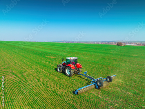 Tractor with a roller tillage on spring field. Aerial view of Soil rolling supports germination and is the basis for good harvesting, organic farming and agronomy