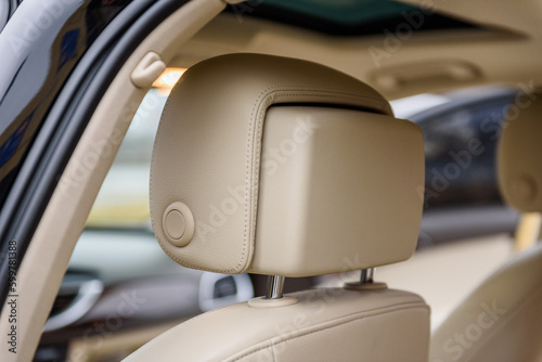 Headrest in the car. Car drivers leather beige seat. Closeup detail. View from behind car seat from back view. Interior of new modern clean expensive car. Seats with nappa leather.