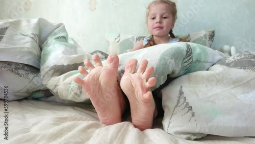 Feet under a light blanket on the bed. Concept of sleeping or waking in the morning
