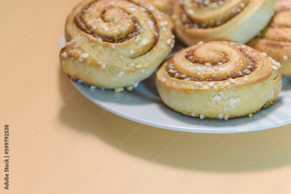 Cinnamon rolls on a white plate with an peach background. close up Cinnamon rolls on a white plate with an peach background. close up