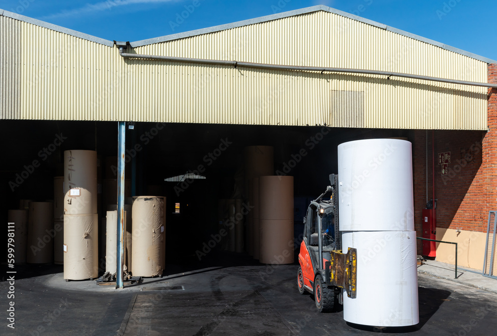 Forklift with clamps to move reels of paper in a warehouse of a paper industry. Forklift with clamps to move reels of paper in a warehouse of a paper industry.