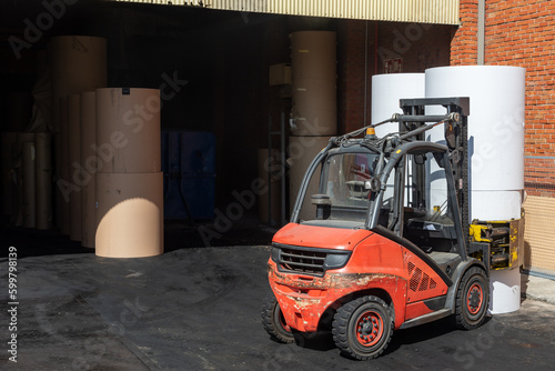 Forklift with clamps to move reels of paper in a warehouse of a paper industry. photo