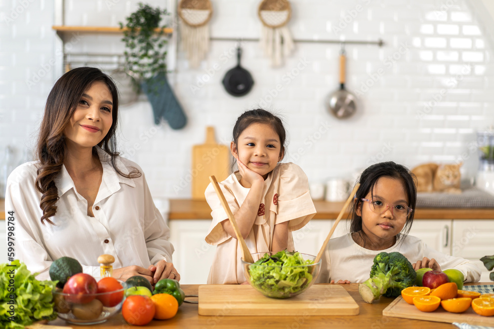 Portrait of enjoy happy love asian family mother with little asian girl daughter child having fun help cooking food healthy eat together with fresh fruit, vegetable salad ingredient in kitchen