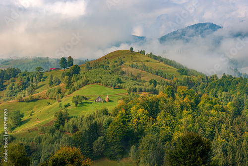 Fototapeta Naklejka Na Ścianę i Meble -  Rural idyllic landscape of the small villages in the Rucar-Bran mountain area, Brasov, Romania, scattered on the wooded hills, with the Bucegi mountains in the background, in wonderful springtime day
