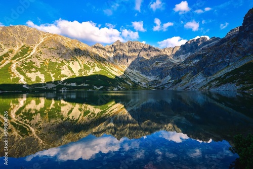 Beautiful summer mountain landscape by the lake. View of the mountains reflecting in the water at Czarny Staw Gasienicowy in the Polish High Tatras.