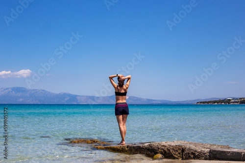 Beautiful body young Woman practicing yoga on a rock in front of the sea, healthy lifestyle, travel, sport concept 