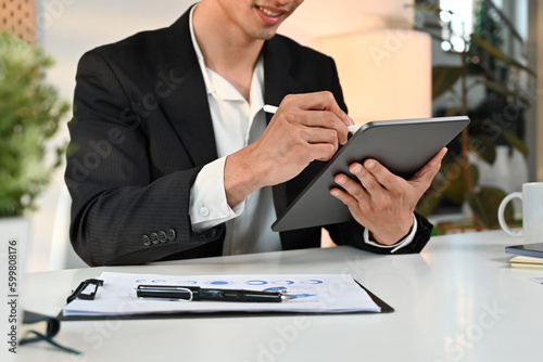 Smiling male entrepreneur analyzing sales statistics management on digital tablet screen