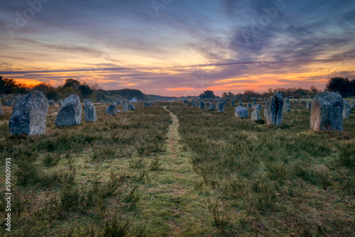chemin au milieu d'un alignement mégalithique, arrangement de menhirs au lever du soleil Carnac, Bretagne, France