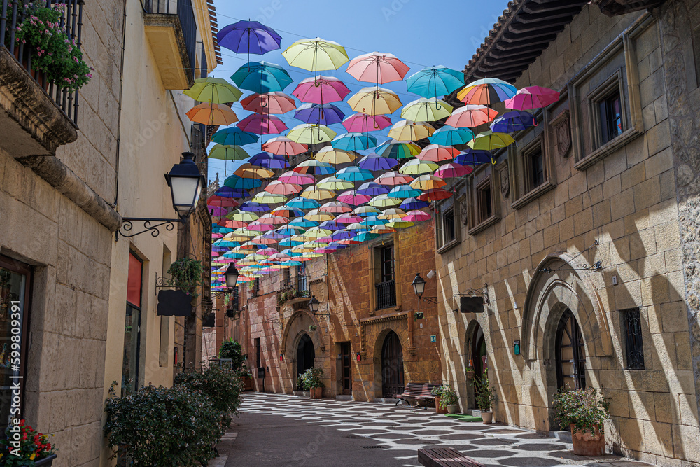 Obraz premium Umbrellas Suspended and Joined with Each other in a Street of Poble Espanyol to Form a Roof of Colorful Umbrellas, Barcelona, Spain