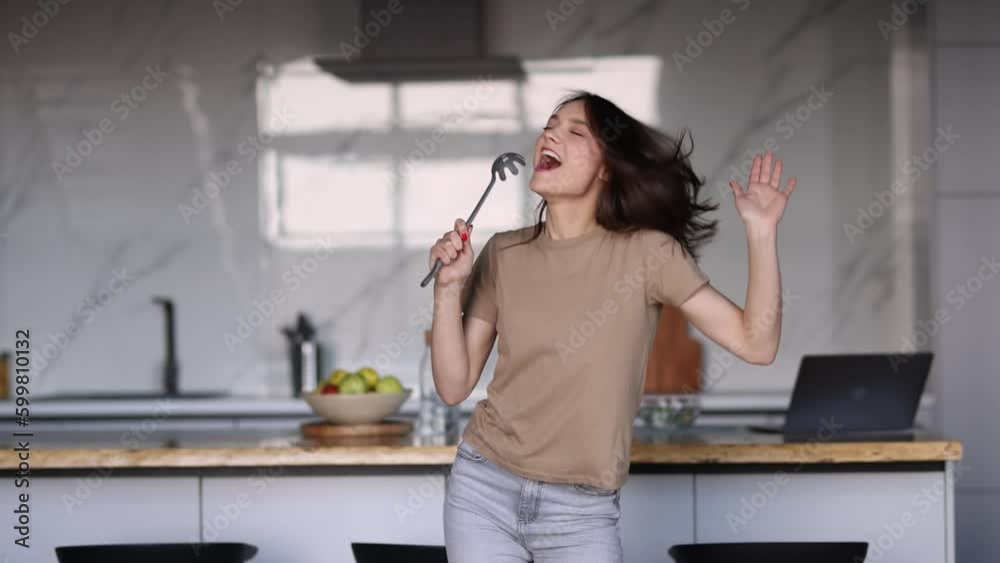 Young woman singing in the kitchen while cooking Young woman singing in the kitchen while cooking
