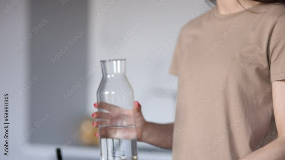 Young woman eat delicious food pout water into the glass while watching screen on laptop in the kitchen Young woman eat delicious food pout water into the glass while watching screen on laptop in the kitchen