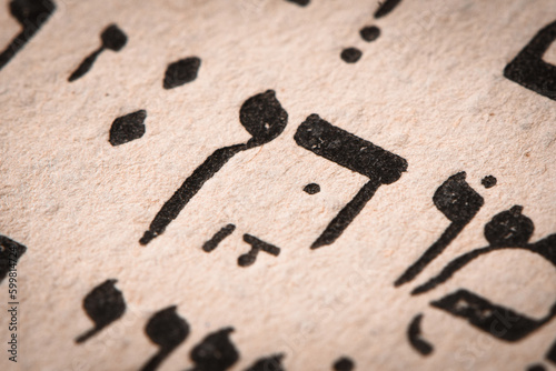 Obraz na płótnie Hebrew word in Torah page. English translation is name Dan, the founder of the Israelite Tribe of Dan. First of the two sons of Jacob and Bilhah. Selective focus. Closeup. w salonie