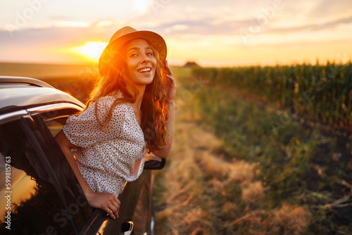 Young woman is resting and enjoying sunset in the car. Summer trip. Lifestyle, travel, tourism, nature, active life.