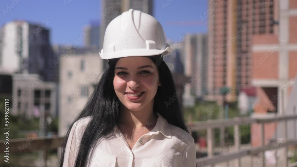 Middle-aged female architect wearing helmet on construction site while working, she smiles at camera and smiles. Successful and proud inspector. Portrait of Female Engineer. Construction Manager Middle-aged female architect wearing helmet on construction site while working, she smiles at camera and smiles. Successful and proud inspector. Portrait of Female Engineer. Construction Manager