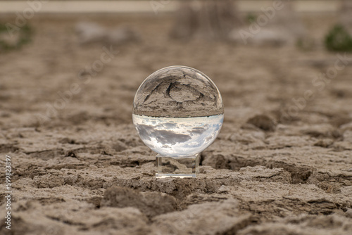Transparent glass ball, dry and cracked land of a lake produced by drought is seen. photo