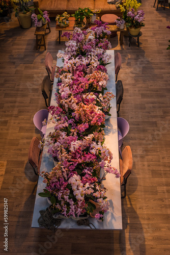 A long table full of arranged flowers photographed from a bird's eye view