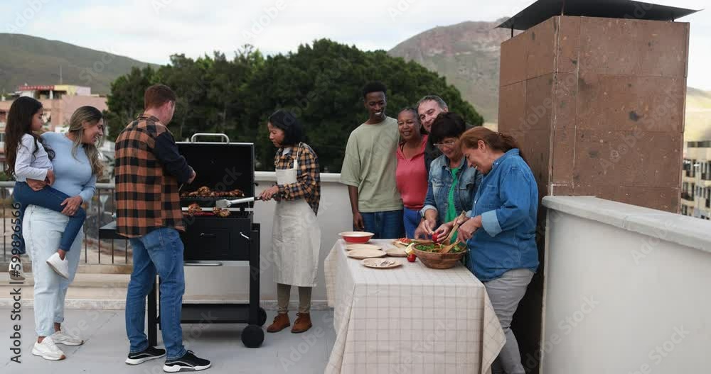 Multi generational people doing barbecue at home's rooftop - Asian woman cooking meat on bbq grill while multiracial friends preparing food during weekend day Multi generational people doing barbecue at home's rooftop - Asian woman cooking meat on bbq grill while multiracial friends preparing food during weekend day