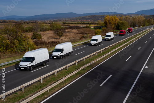 Wallpaper Mural White and red minivans are moving in a convoy on the highway.  White and red modern delivery small shipment cargo courier van moving fast on motorway road to city urban suburb. Torontodigital.ca