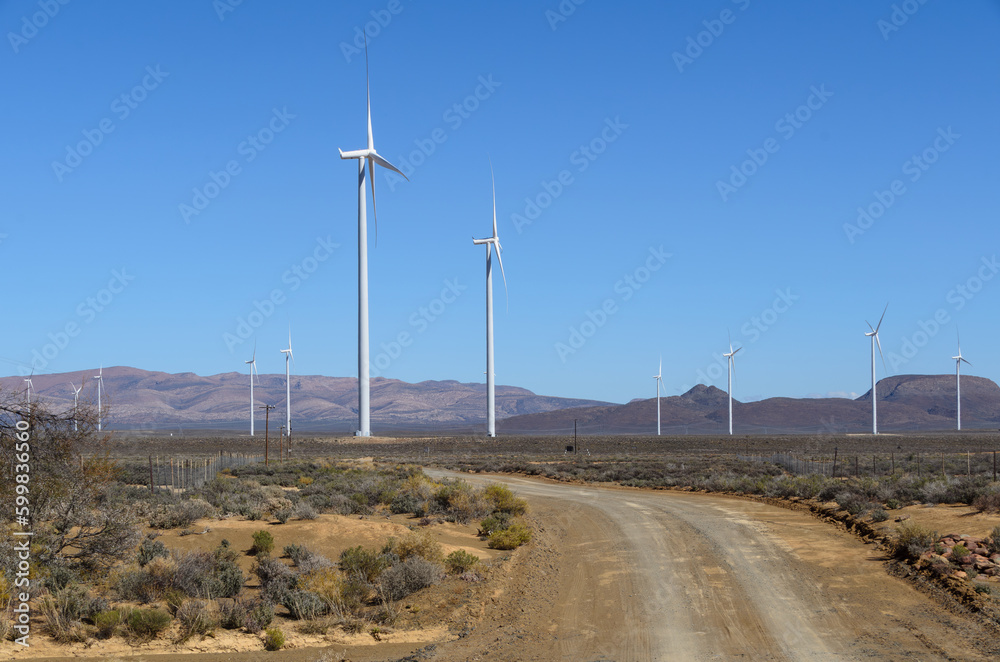 Wind turbines farm next to a gravel road