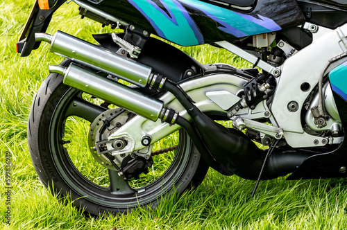 Earsham, Norfolk, UK – April 30 2023. The rear wheel, tyre and twin exhaust system of a Suzuki RGV250 2 stroke race replica sports motorbike