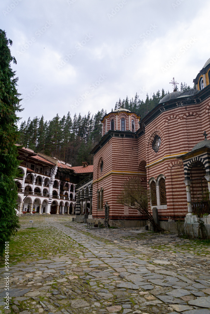 Cloister of the Rila Monastery in Bulgaria, it has many arches and columns, many paintings and frescoes, it is very colorful, photo on a cloudy day. Cloister of the Rila Monastery in Bulgaria, it has many arches and columns, many paintings and frescoes, it is very colorful, photo on a cloudy day.