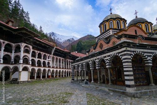Rila Monastery in Bulgaria, without tourists and without people, on a day with some clouds, and with the snowy mountain in the background.