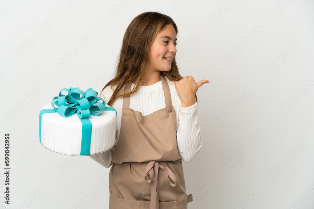 Little girl holding a big cake over isolated white background pointing to the side to present a product Little girl holding a big cake over isolated white background pointing to the side to present a product