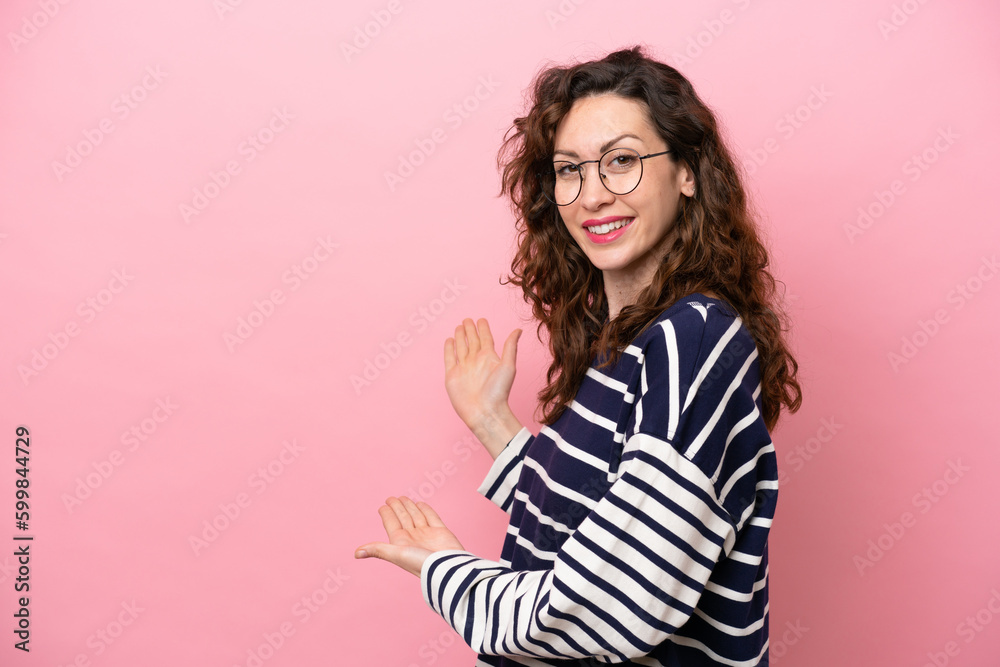 Young caucasian woman isolated on pink background extending hands to the side for inviting to come