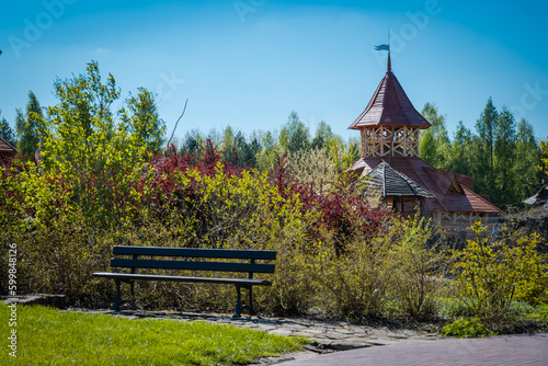 A wooden tower in a grove between trees by a bench.