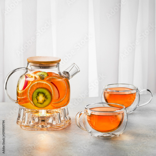 Fruit tea with oranges, mint  in a glass kettle ( teapot) on white