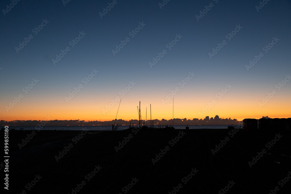 Naklejka premium Wide angel views of a beach in the Riviera Romagnola area in Italy, with its red flaming colors and boat poles in the distance.