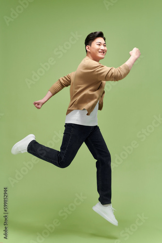 Full size photo of young happy excited crazy positive man jumping hold fists in victory