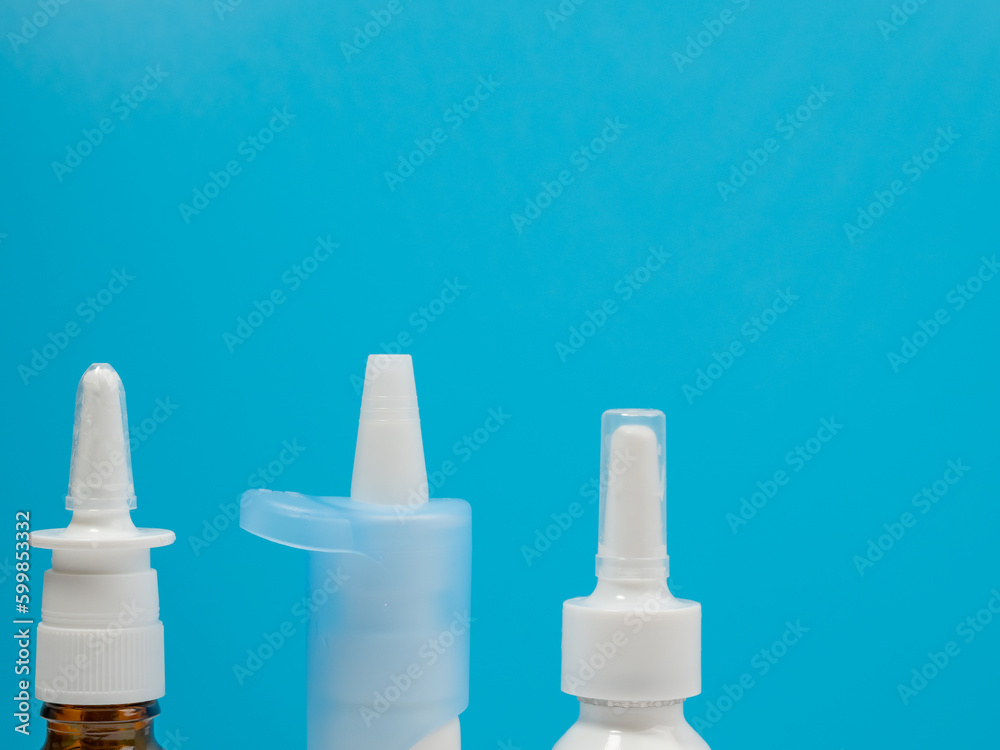 Nasal spray bottles on a blue background, treating a cold with a nasal spray. Medicine close-up. Nasal spray bottles on a blue background, treating a cold with a nasal spray. Medicine close-up.