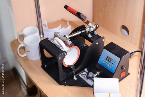 The process of baking souvenir cups in special thermopress, making souvenir mugs, with an image on them, focus on the thermopress and the cup