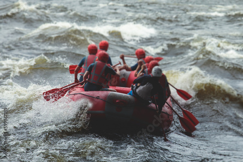 Red raft boat during whitewater rafting extreme water sports on water rapids, kayaking and canoeing on the river, water sports team with a big splash of water